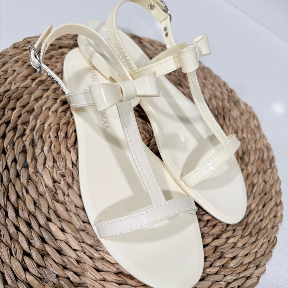 Stuart Weitzman Mellie Bow Jelly Sandals in a white or cream color.